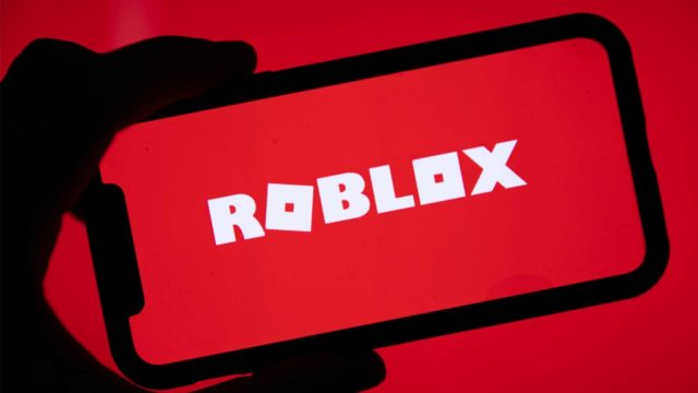 Foto: Shutterstock / Ink Drop. Bildet viser Roblox-logoen på en mobilskjerm, både skjermen og bakgrunnen er rød.