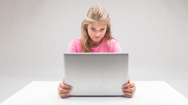 Foto: Shutterstock / Giulio_Fornasar. Bildet viser ei jente som ser på en dataskjerm. Ansiktet viser at hun ikke liker det hun ser.