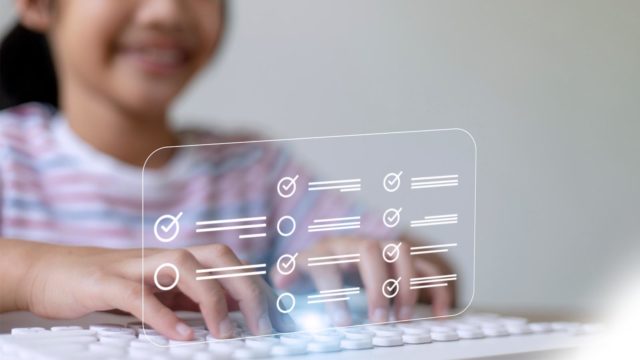 Foto: Shutterstock / FAMILY STOCK. Bildet viser ei jente som skriver på et tastatur.En slags gjennomsiktig skjerm viser avkrysningsbokser.