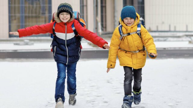 Foto: Shutterstock / Irina Wilhauk. Bildet viser to elever med ransel, som løper på snøen.